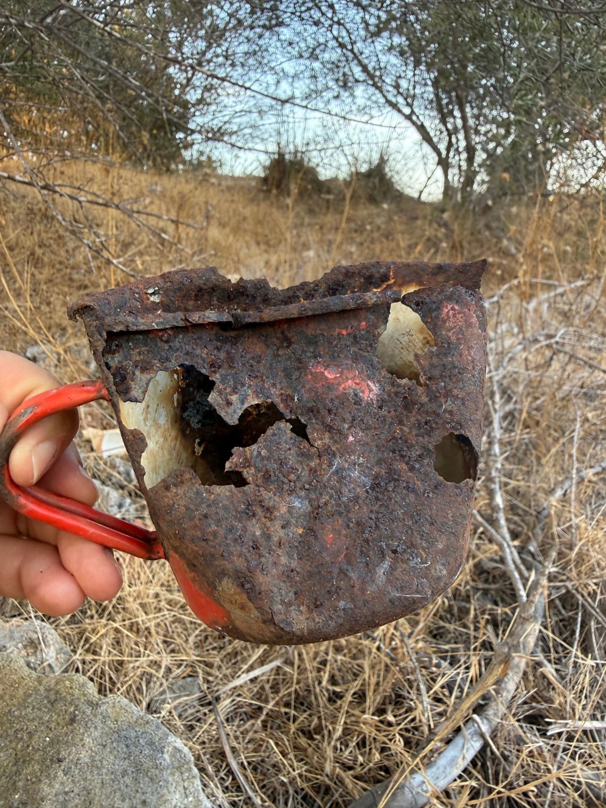 ritrovamento di una tazza in metallo schiacciata e arrugginita
